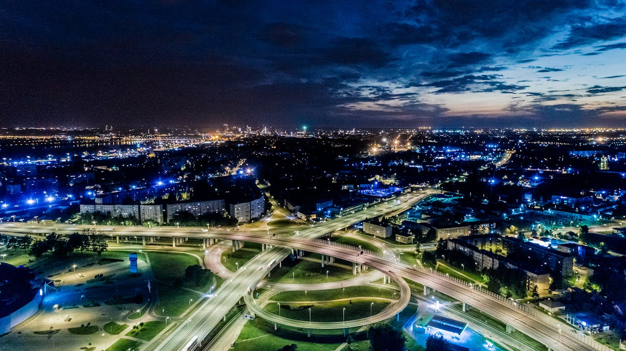 services-02 Vibrant cityscape aerial view of illuminated highways and urban skyline at twilight.
